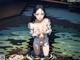 A naked woman standing in a pond of water.