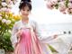 A woman in a pink and white hanbok posing for a picture.