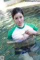 A woman in a green and white shirt is standing in the water.