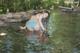 A woman in a blue and white striped bikini is standing in the water.