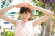 A woman in a pink tank top standing in front of a palm tree.