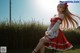 A woman in a red dress sitting on a chair in a field.