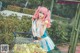 A woman with pink hair holding a tennis ball in a shopping cart.