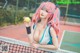 A woman with pink hair holding a tennis ball.