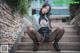 A woman sitting on the steps of a building wearing black stockings.